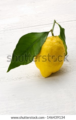 Single fresh yellow lemon with a stalk and leaf with its sour tangy taste and high in vitamin c it is used as a flavoring, cooking ingredient and garnish