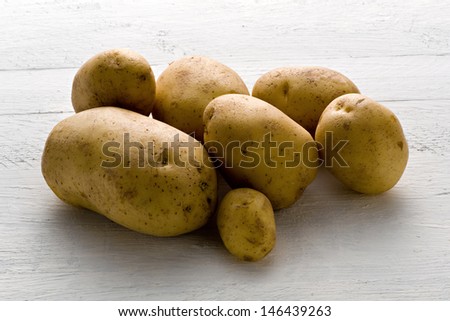 Pile of whole raw farm fresh potatoes of differing sizes displayed on a white background