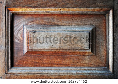 Closeup background of an old teak wooden panel with raised centerpice for mounting a plaque or name plate