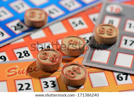 Bingo cards and numbered tokens to be drawn at random and marked off until the cards are full, close up background view