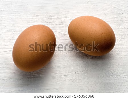 Closeup of two brown chicken eggs, healthy natural source of proteins, on a wooden surface