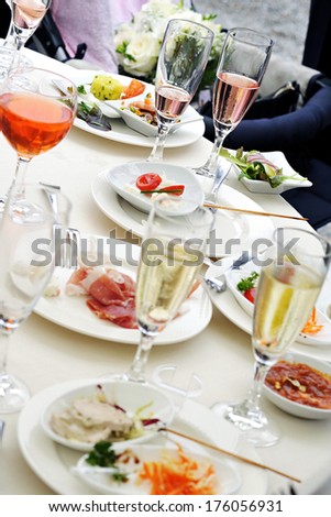 People at a dinner party - view of the table with an array of different wines, drinks or champagne in glasses and starters on plates chosen by each individual