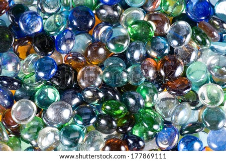 Background pattern and texture of shiny reflective multicolor glass drops with smooth rounded edges in a random pile