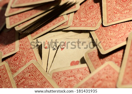 Vintage deck of poker playing cards with four aces in the center face upwards surrounded by the rest of the deck scattered randomly with the pattern showing