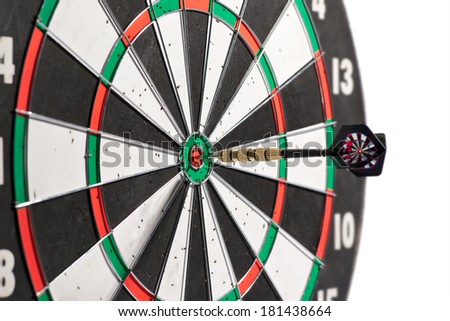 Dart in the center of a dart board scoring a bulls eye conceptual of winning, accuracy, skill, challenge and achievement, isolated on white
