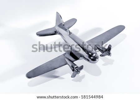 Silver model toy airplane with twin engines with propellers, high angle view on a white background with shadow and copy space