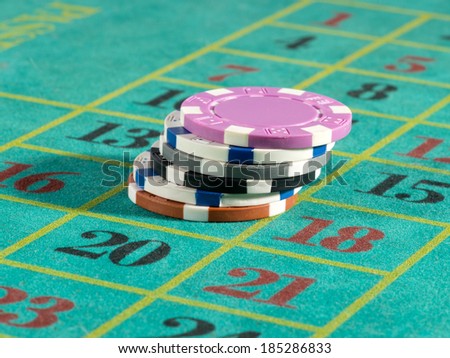 Stack of casino chips or tokens on a numbered roulette board in payment of a bet in a gambling game of luck and chance