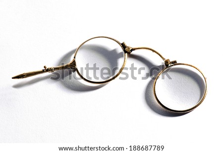 Pair of vintage lorgnettes or spectacles with a small handle on the eyeglass for use when reading or at the opera, on a white background