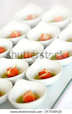 Individual servings of fresh salad appetizers at a catered event arranged on a tray in diagonal rows , close up view