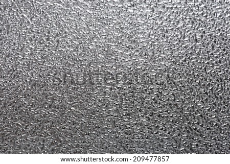 Background metal texture of a rough metal sheet with a shiny metallic surface reflecting light and stippled pattern, closeup detail