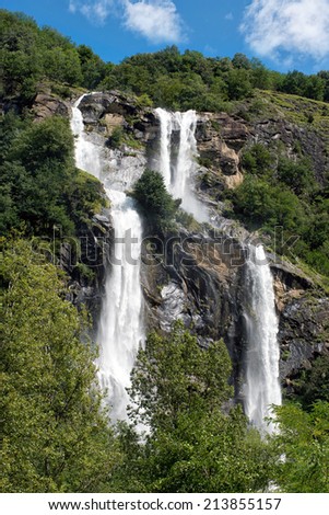 Twin waterfall cascading down a mountainside over a steep rocky cliff in plumes of white water in a scenic landscape