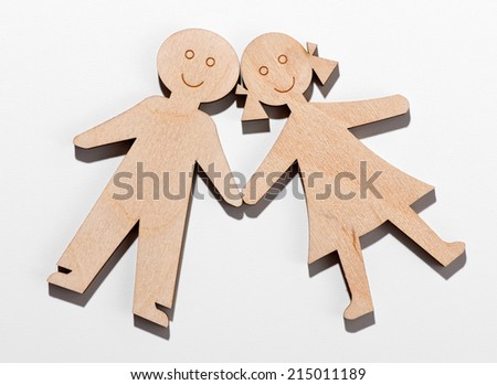 Two rustic wooden children cut out shapes with happy smiling faces lying obliquely on a white background with their hands touching, young boy and girl