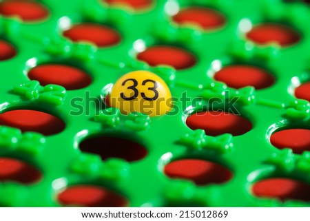 Single number on a yellow plastic ball in a green and red bingo board