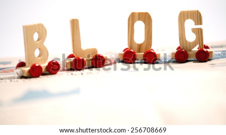 Blog and communication concept with the word - blog - in wooden alphabet letters on wooden bases with red wheels on a white background with copy space