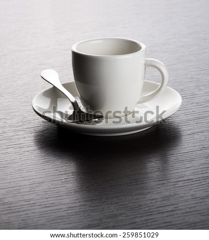 Close Up of Empty White Mug on Saucer with Silver Spoon on Dark Wooden Table with Visible Wood Grain
