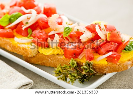Mediterranean bruschetta or finger snacks served as appetizers with diced fresh spicy tomato and onion on sliced baguette