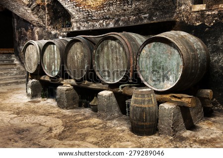Row of old wooden oak barrels in a wine cellar on a winery for the production and maturing of local wines