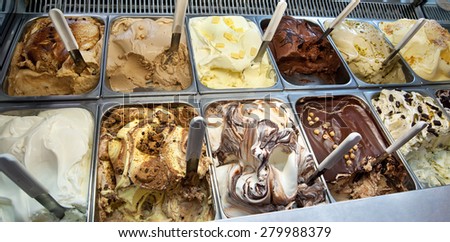 Display window in a store or ice cream parlour of assorted ice cream flavors for sale as summer takeaways displayed in metal trays with scoops