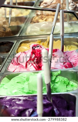 Colorful display of an assortment of different flavors of fruity Italian ice cream in metal containers in a shop or ice cream parlour for summer takeaways