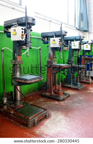 Row of freestanding bench drills in a factory or engineering workshop for industrial manufacturing and production