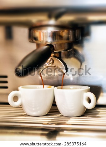 Coffee machine dispensing a double Italian espresso into two small cups in a coffee house or restaurant