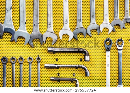 Neat arrangement of tools on yellow pegboard in a workshop with spanners, wrenches and sockets