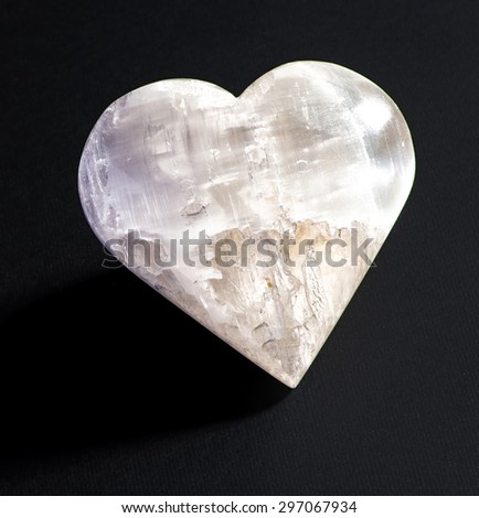 Heart shaped stone with grey texture on a black background with copy space for your romantic message of love for Valentines Day or an anniversary celebration