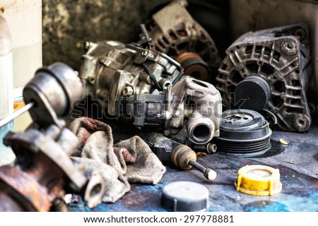 Old obsolete discarded motor vehicle components in an automotive workshop lying in a heap on the floor waiting to be disposed of following repairs and maintenance