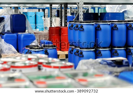 Colorful red metal and blue plastic barrels or drums stored in a warehouse stacked on top of one another for retail packaging for industrial supplies