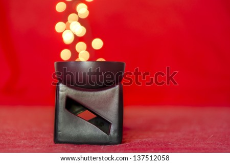 ceramics decorative candle holder on red background with lights coming out of it