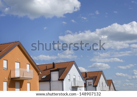 roofs of houses in different colors under blue sky with clouds above