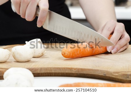 hands chopping carrots on a wooden chopping board