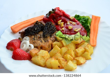 Close up of pork steak with Morel mushrooms, French recipe,  on white plate with French fries, red pepper in olive oil with garlic, vegetables and strawberries