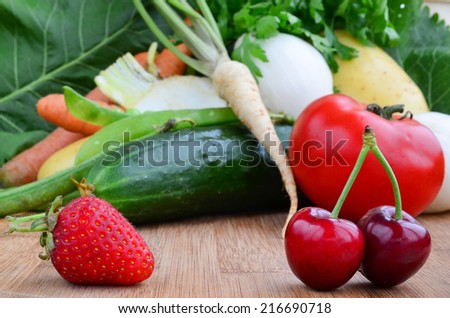 Strawberry and cherries in foreground and vegetables in background, shallow depth of field