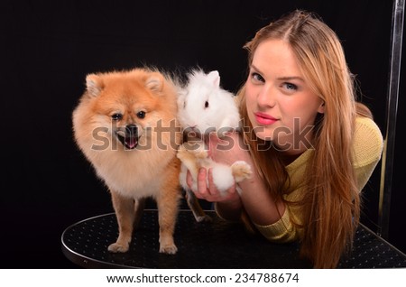 Young, pretty pet hairdresser posing with Pomeranian dog and white rabbit
