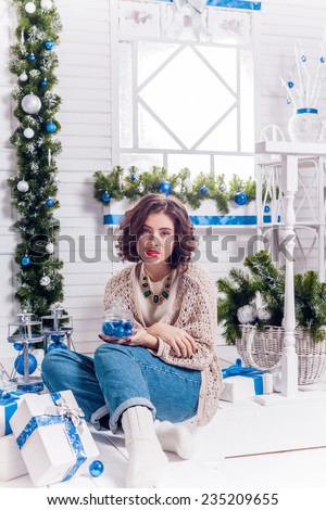 girl in Christmas decorations on the porch holding a New Year\'s toys