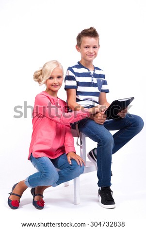 smiling schoolchildren learn about the world and communicate with the help of modern tablets and phones, an interesting training and gadgets.Photo from the depth of field on a white background