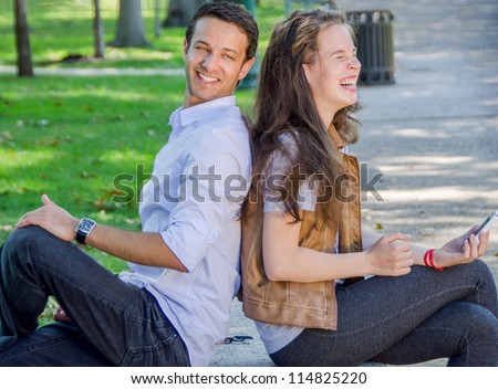 Young Man and Women Flirt on Bench in a Park