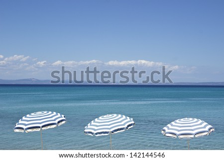 Three vintage umbrellas over the blue sea water