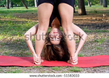 Standing forward fold yoga pose in the park