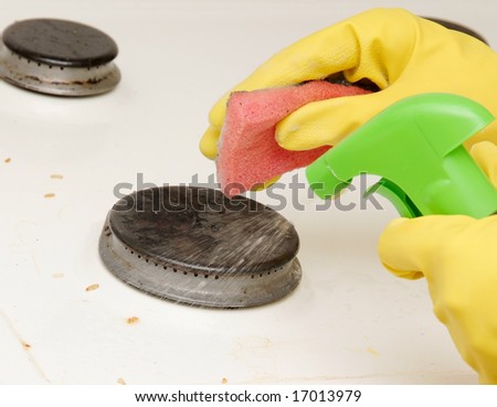 Hands in gloves washing cooking oven with sponge and liquid.