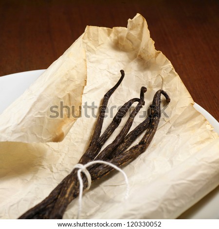 vanilla beans in old paper with wooden background