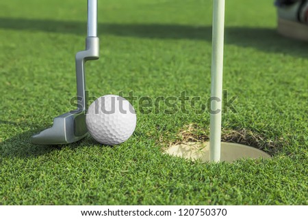 putter puts a golf ball to hole on green of golf course