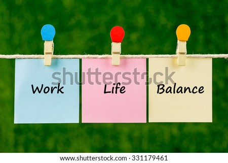 Words of Work Life Balance on sticky color papers hanging by a rope against blurred green background.