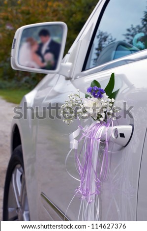 The wedding car with registration and reflection of a newly-married couple in a rear-view mirror