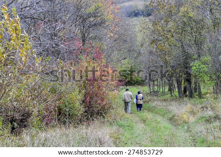 picture showing two persons walking on a natural path bordered by trees somewhere in rural Transylvania, Romania