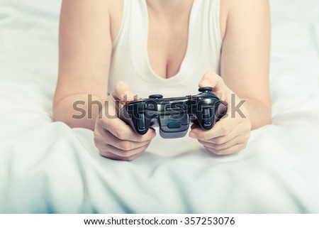 Young caucasian woman playing video game console lying on the bed