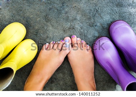 Female legs next to colorful boots for a rainy day