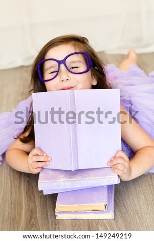 Cute girl in the glasses holding a purple book