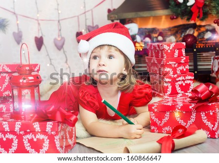 Smiling child in a cap of Santa Claus with holiday wish list